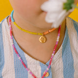 Close-up of a girl wearing the Daisy Necklace with hand-painted golden pendant and thread chain with crystals.