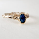 10k yellow gold ring with a Montana sapphire and two lab-grown diamonds set in an organic sculpted band, shown front-facing on a white background.