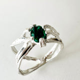 Sterling silver ring with a lab-grown emerald set in an organic sculpted band, shown front-facing on a neutral background.