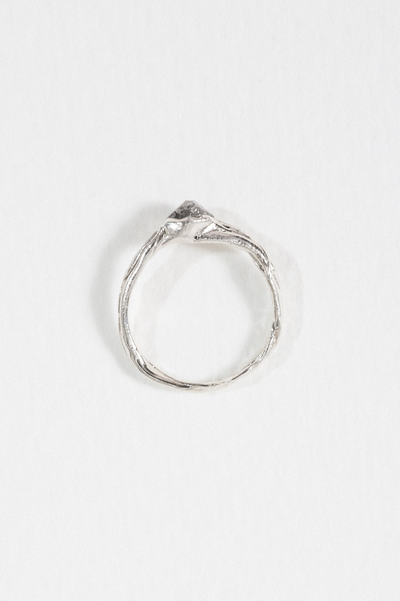 Top view of a silver ring with a hammered band and a raised, irregular stone detail.