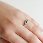 Hand wearing a silver ring with a green gemstone, showing the delicate and minimalist design.