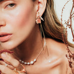 Red elderberry earrings in gold-plated brass with botanical texture, worn by a model with a light background and plant composition.