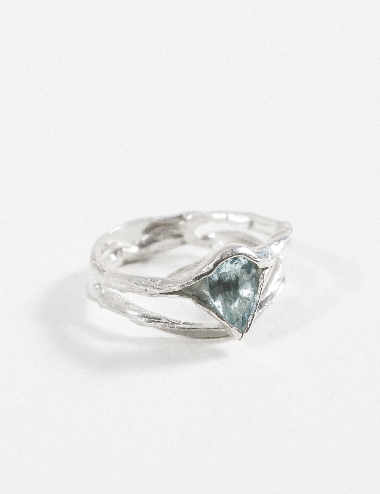 Side-angled view of the sterling silver ring with a faceted aquamarine gemstone.