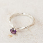 Top view of the sterling silver ring with a 4mm amethyst, placed on neutral fabric, highlighting its organic handcrafted texture.