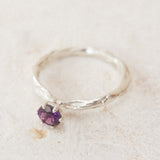 Top view of the sterling silver ring with a 4mm amethyst, placed on neutral fabric, highlighting its organic handcrafted texture.