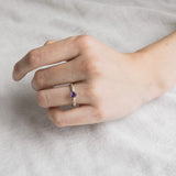 Woman’s hand wearing the sterling silver amethyst ring, showing the fit and delicate profile of the 4mm gemstone against a soft background.