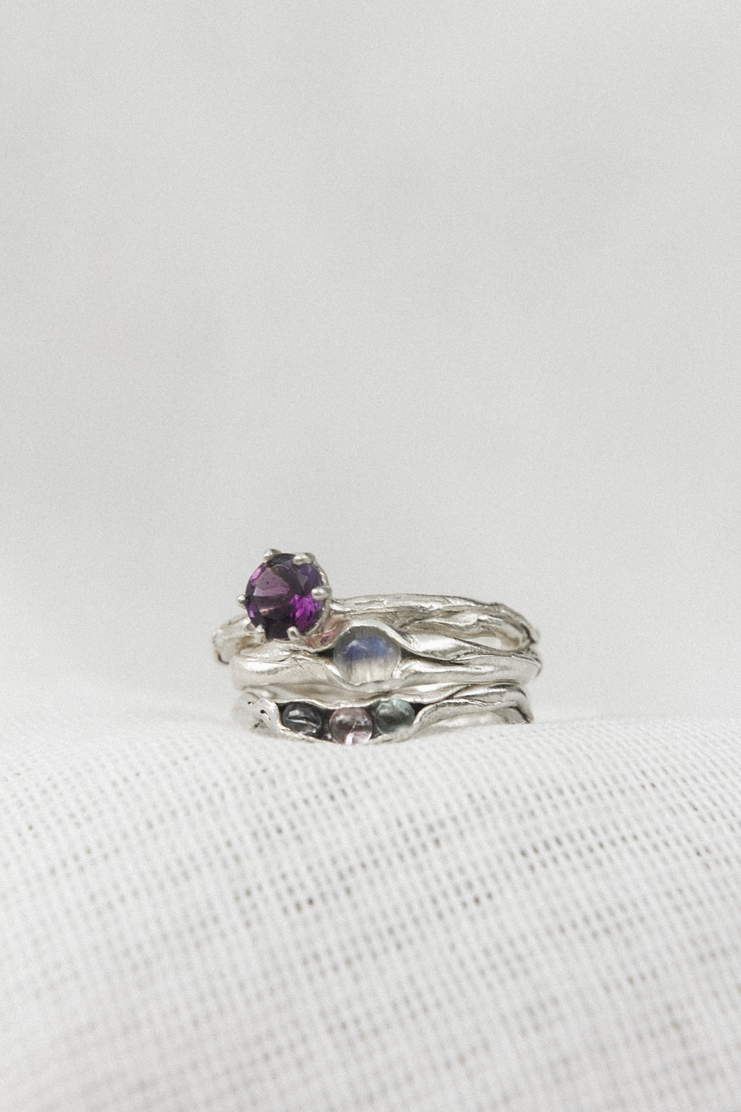 Sterling silver amethyst ring stacked with two additional textured silver bands, displayed on a white background.