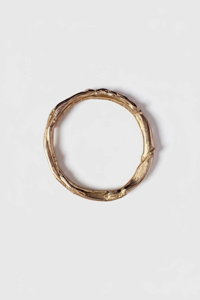 Gold ring with a natural, organic texture on a light gray background