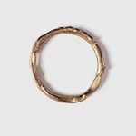 Gold ring with a natural, organic texture on a light gray background