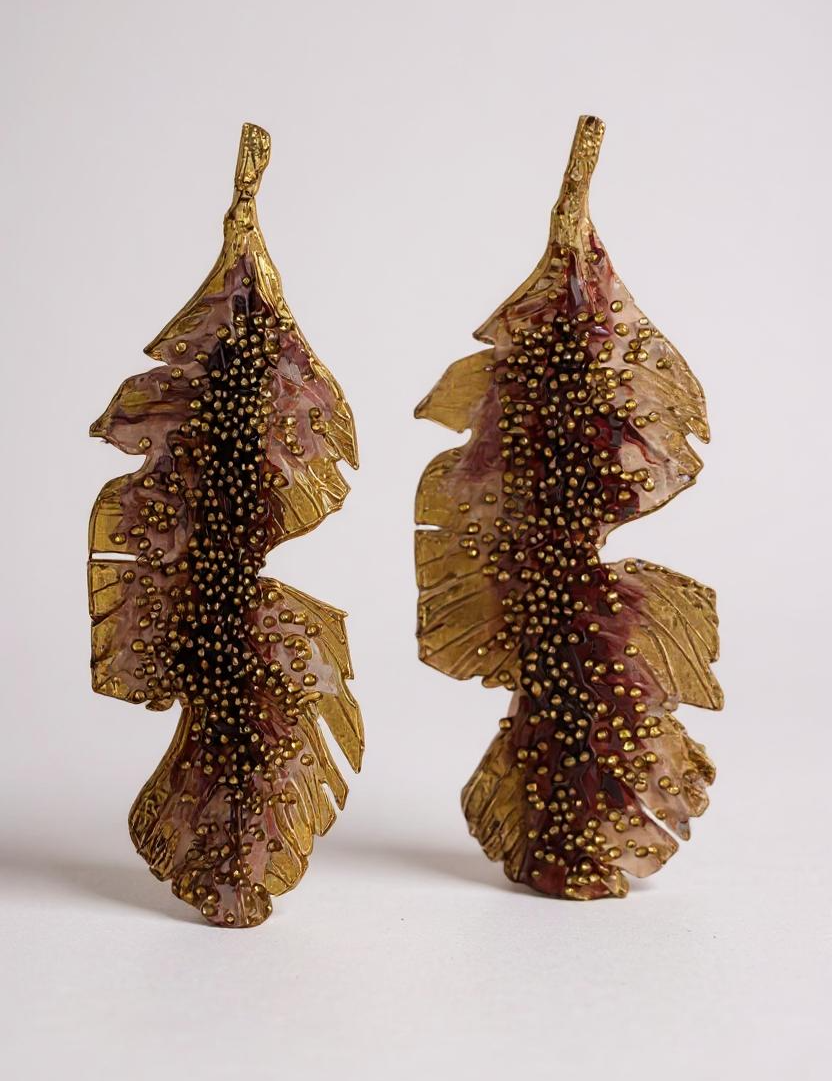 Pair of Banana Leaf Earrings in gold-plated brass hand-painted rust with glass granulation detail, displayed against a white background.