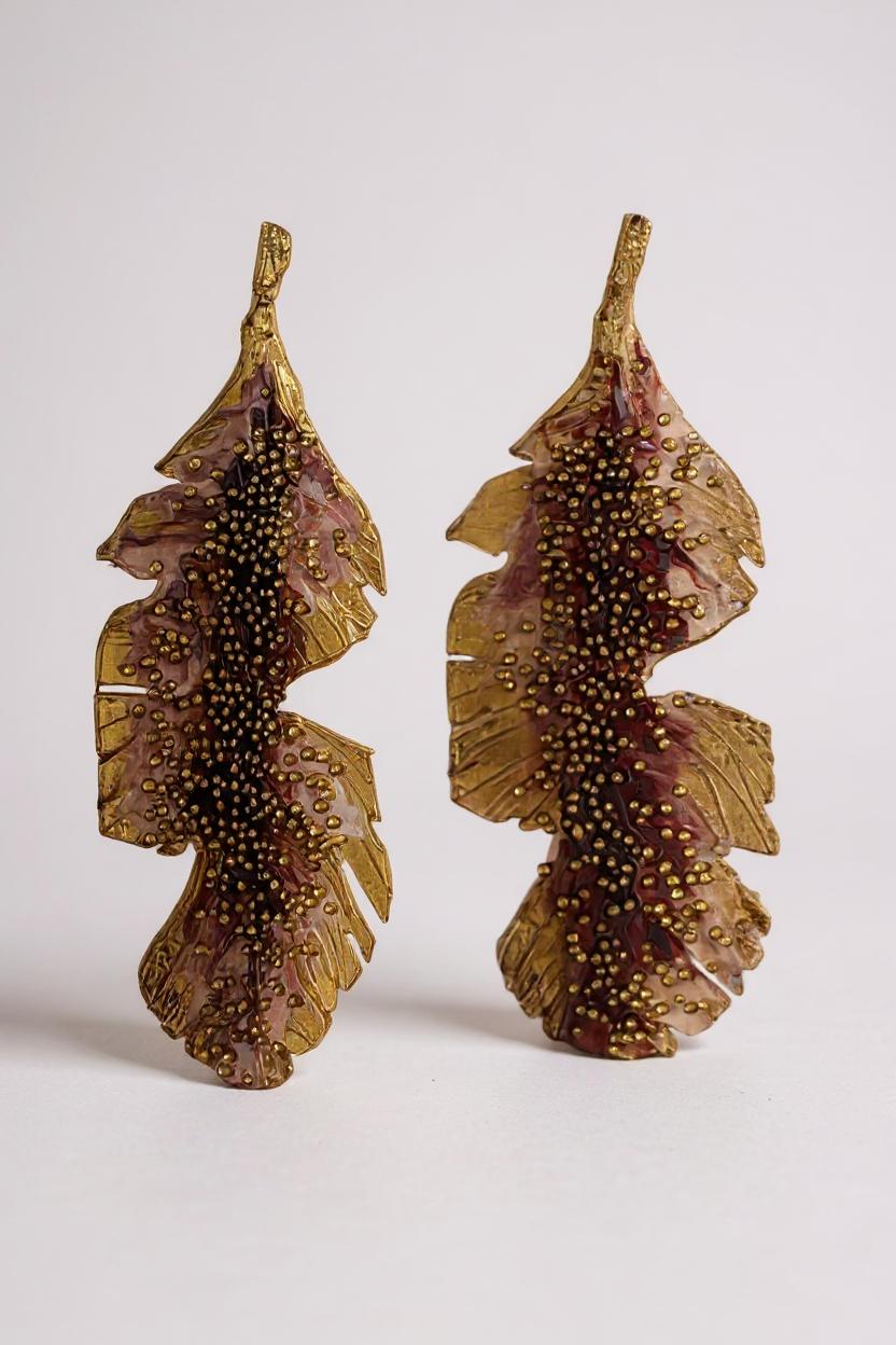 Pair of Banana Leaf Earrings in gold-plated brass hand-painted rust with glass granulation detail, displayed against a white background.