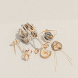 Flat lay of ocean-inspired jewelry, including gold-dipped shells, pearl and gemstone necklaces, earrings, and hairpins, displayed on a white textured surface.