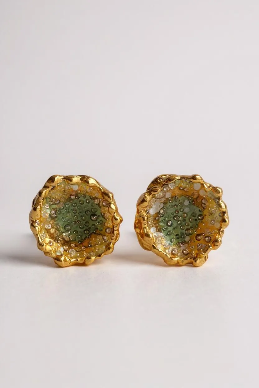 Flat lay of a pair of Topos Coca M stud earrings in gold-plated brass, hand-painted in sage-green with glass granulation, on a white background.