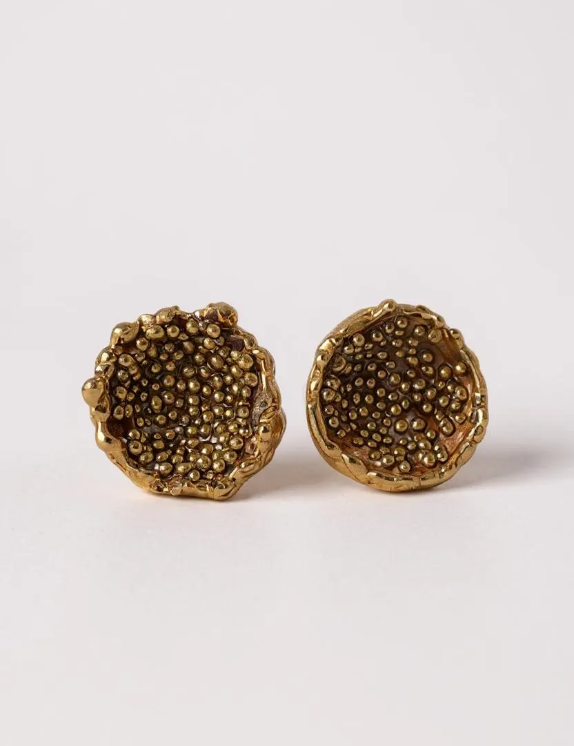 “Flat lay of a pair of Topos Coca M stud earrings in gold-plated bronze, hand-painted in rust with glass granulation, on a white background.