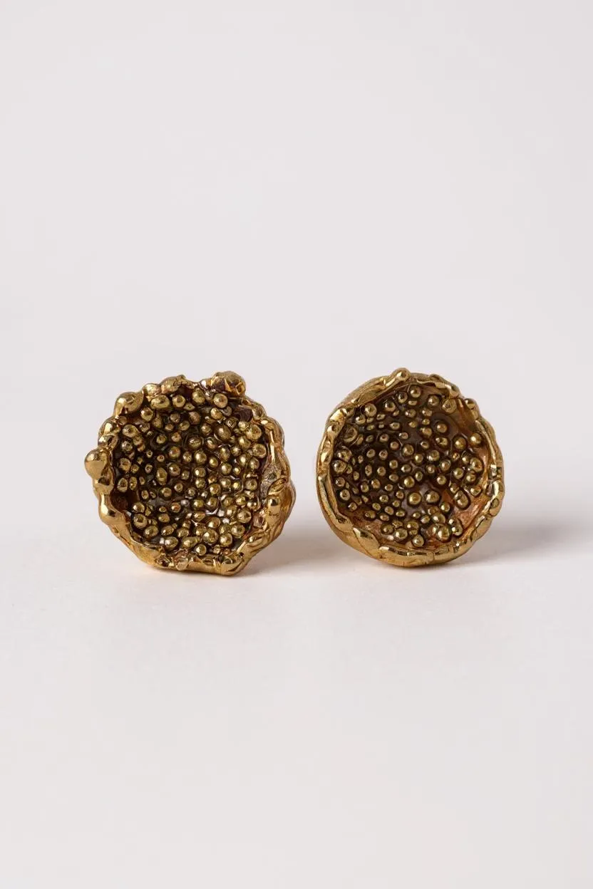 “Flat lay of a pair of Topos Coca M stud earrings in gold-plated bronze, hand-painted in rust with glass granulation, on a white background.