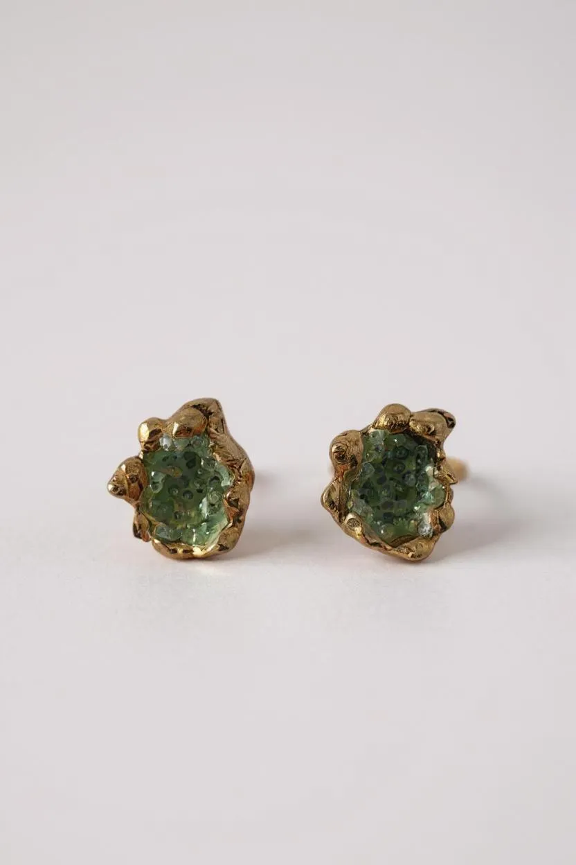 Pair of Topos Coca S stud earrings with green glass granulation and paint in scalloped gold-tone bezels, displayed on a white background.