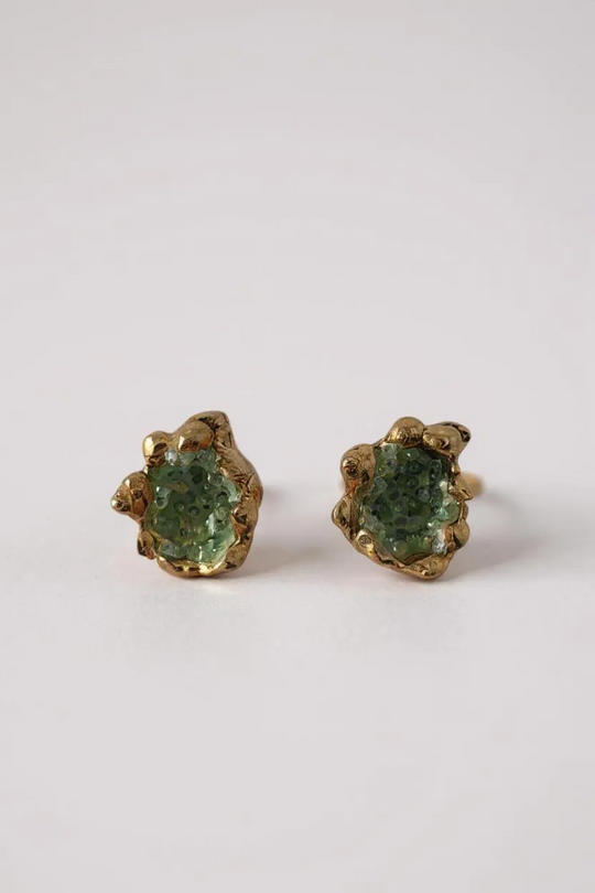 Pair of Topos Coca S stud earrings with green glass granulation and paint in scalloped gold-tone bezels, displayed on a white background.