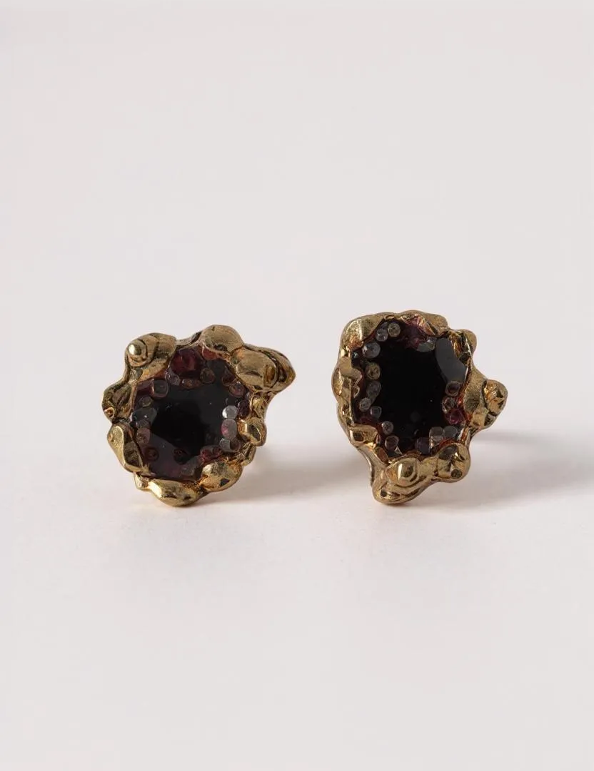 Pair of Topos Coca S stud earrings with rust paint and glass granulation in gold-tone settings, displayed on a white background.
