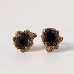 Pair of Topos Coca S stud earrings with rust paint and glass granulation in gold-tone settings, displayed on a white background.