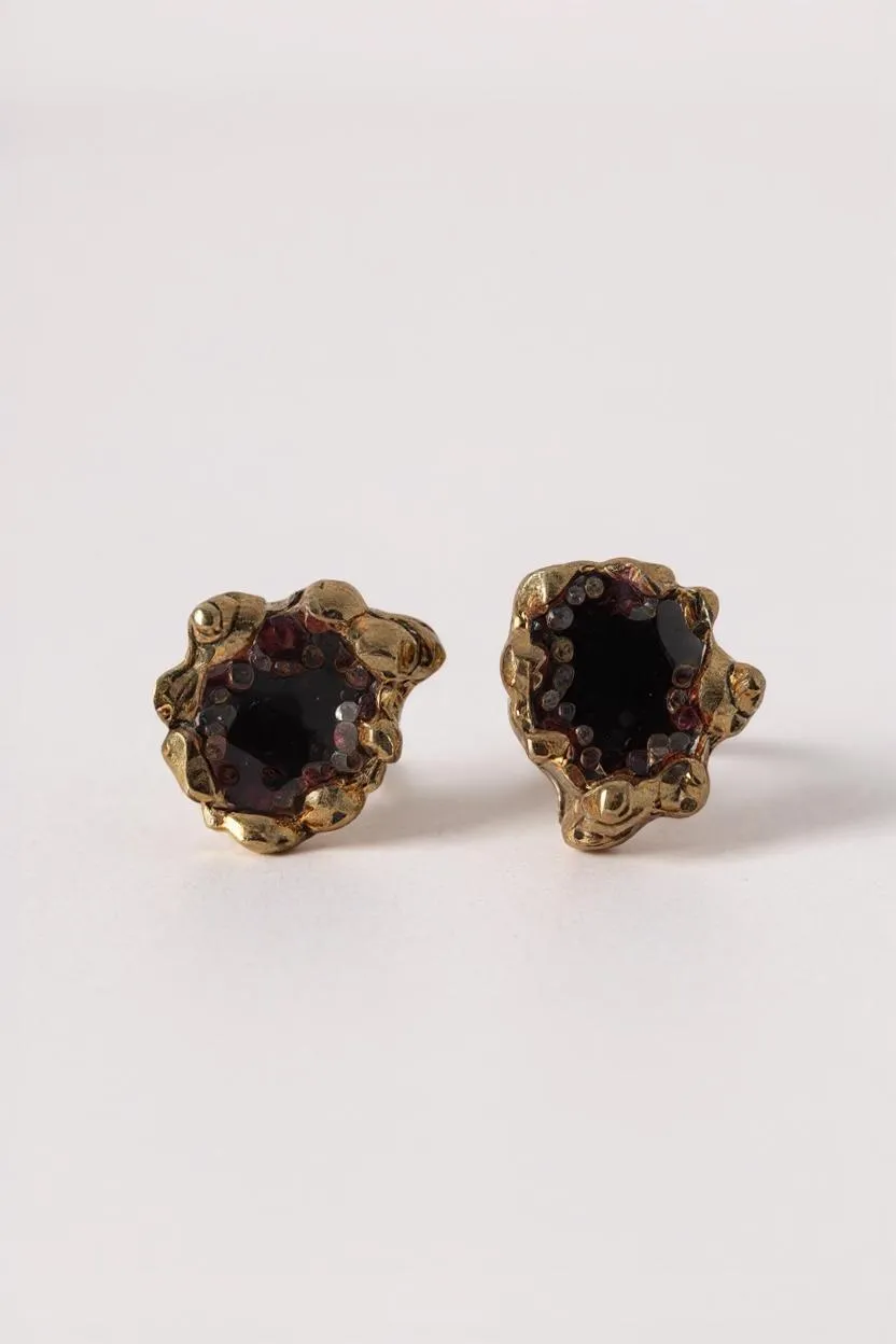 Pair of Topos Coca S stud earrings with rust paint and glass granulation in gold-tone settings, displayed on a white background.