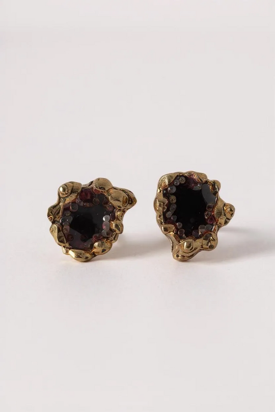 Pair of Topos Coca S stud earrings with rust paint and glass granulation in gold-tone settings, displayed on a white background.