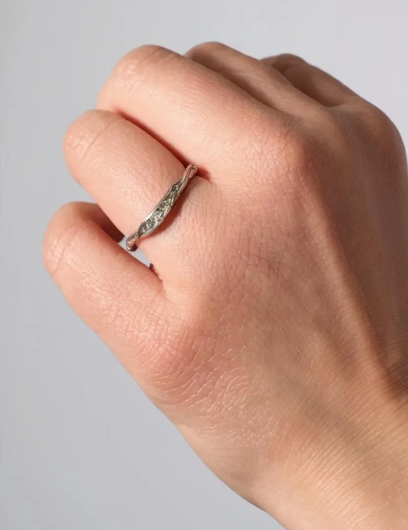 Silver ring with lab-grown diamonds worn on a finger, showing how it looks when worn.
