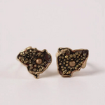 “Pair of Topos Cucu stud earrings in rust paint with glass granulation on gold-plated bronze, displayed on a soft pink background.