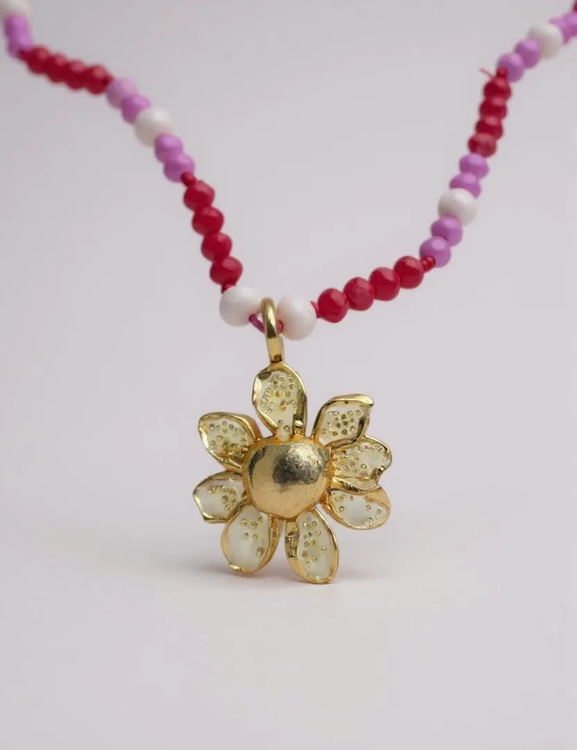 Daisy necklace in gold-plated bronze with hand-painted pendant and pink and fuchsia crystals, on white background.