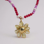 Daisy necklace in gold-plated bronze with hand-painted pendant and pink and fuchsia crystals, on white background.