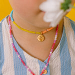 Close-up of a girl wearing the Daisy Necklace with hand-painted golden pendant and thread chain with crystals.