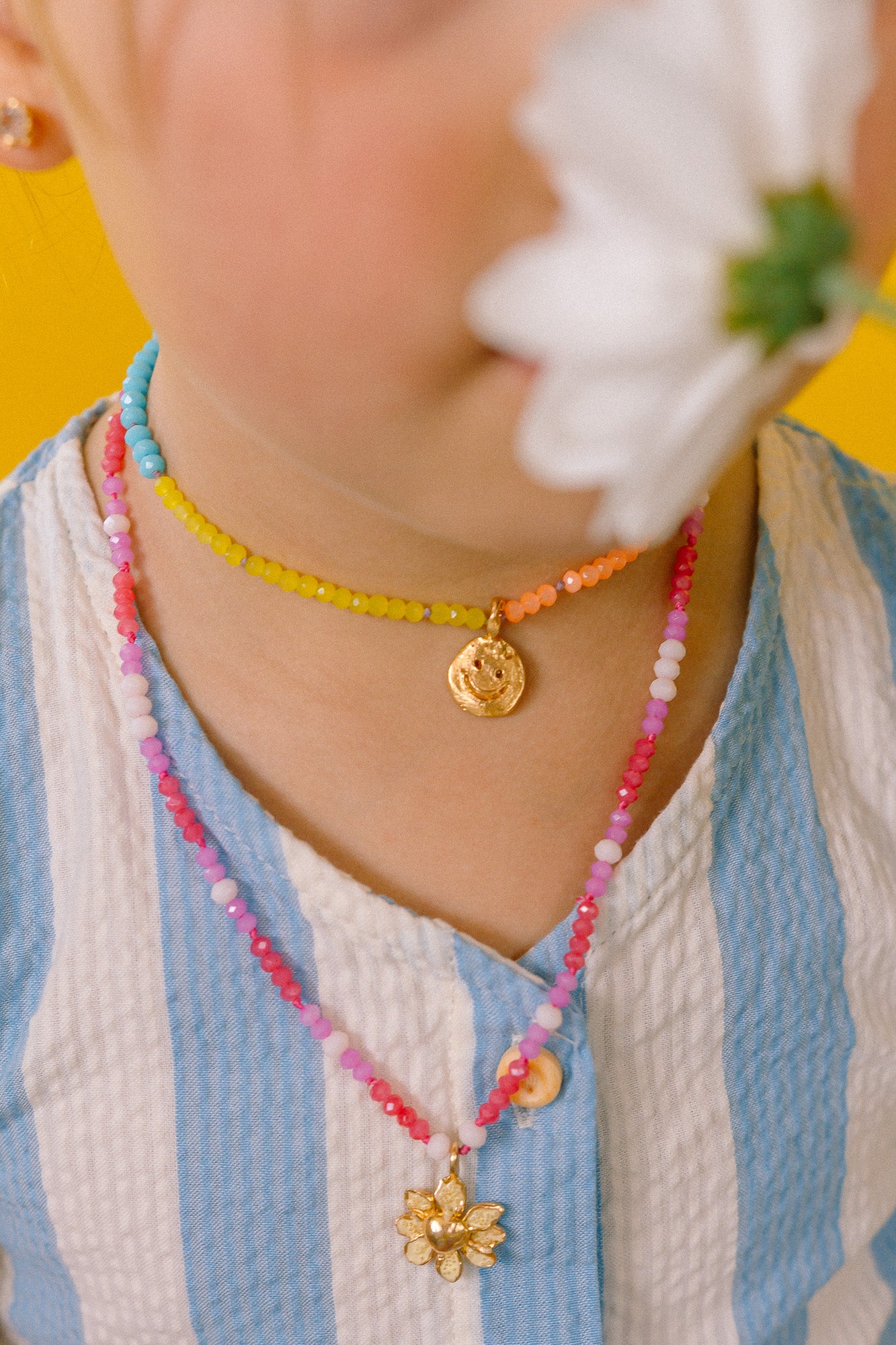 Close-up of a girl wearing the Daisy Necklace with hand-painted golden pendant and thread chain with crystals.