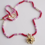 Handmade Daisy Necklace with golden flower pendant, arranged in a circle on white background.