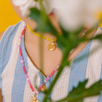 Close-up of the Margarita Necklace golden pendant surrounded by pink, white, and fuchsia crystals.