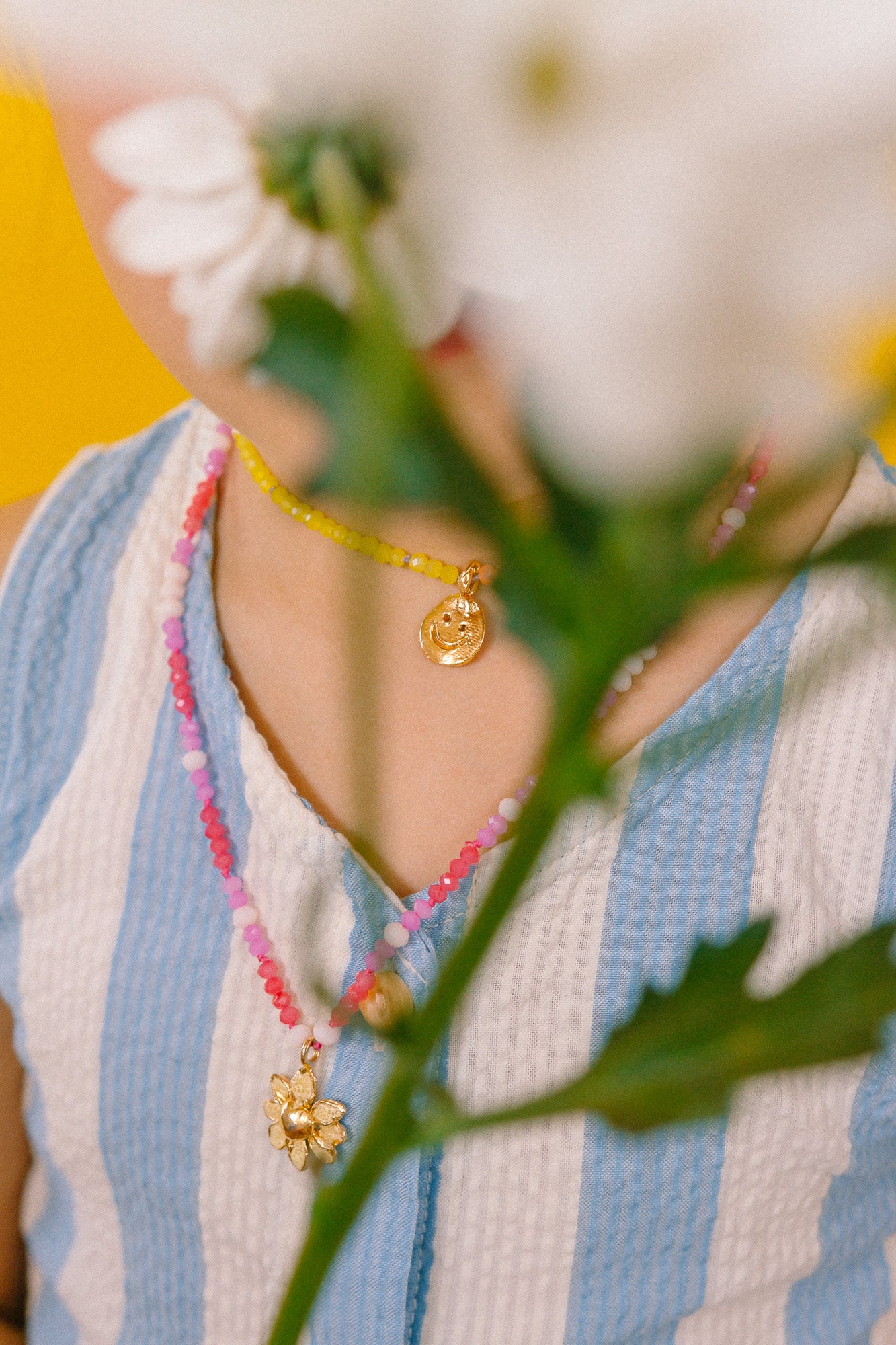 Close-up of the Margarita Necklace golden pendant surrounded by pink, white, and fuchsia crystals.