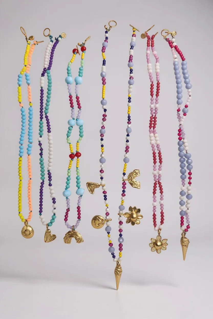 Set of colorful beaded necklaces with various pendants on a light gray background