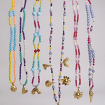 Set of colorful beaded necklaces with various pendants on a light gray background