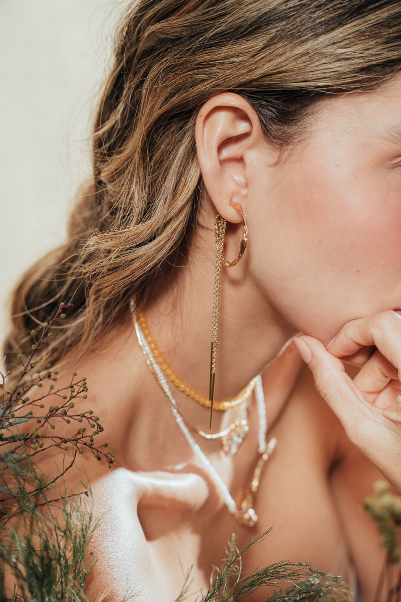 Close-up detail of the Espiga hoops worn by the model, highlighting the organic shape and artisanal character of the piece.