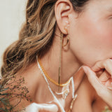 Close-up detail of the Espiga hoops worn by the model, highlighting the organic shape and artisanal character of the piece.