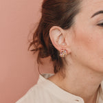  Profile of a woman wearing a Galaxea earring in Rust color, gold-plated with glass granules, hair pulled back, against a soft terracotta background.