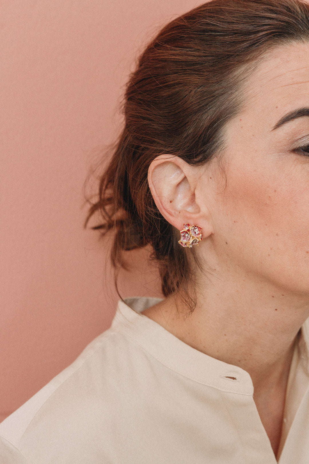  Profile of a woman wearing a Galaxea earring in Rust color, gold-plated with glass granules, hair pulled back, against a soft terracotta background.