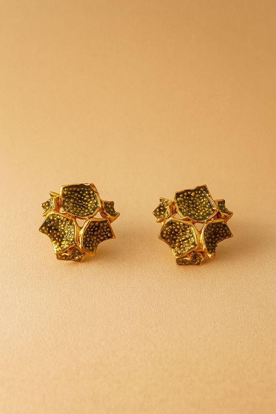 Two Galaxea sage stud earrings—gold-plated floral-shaped studs with sage-green glass granules—positioned side by side on a warm beige background.