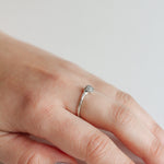 Hand wearing a handcrafted silver ring with a textured finish and an artisanal look.