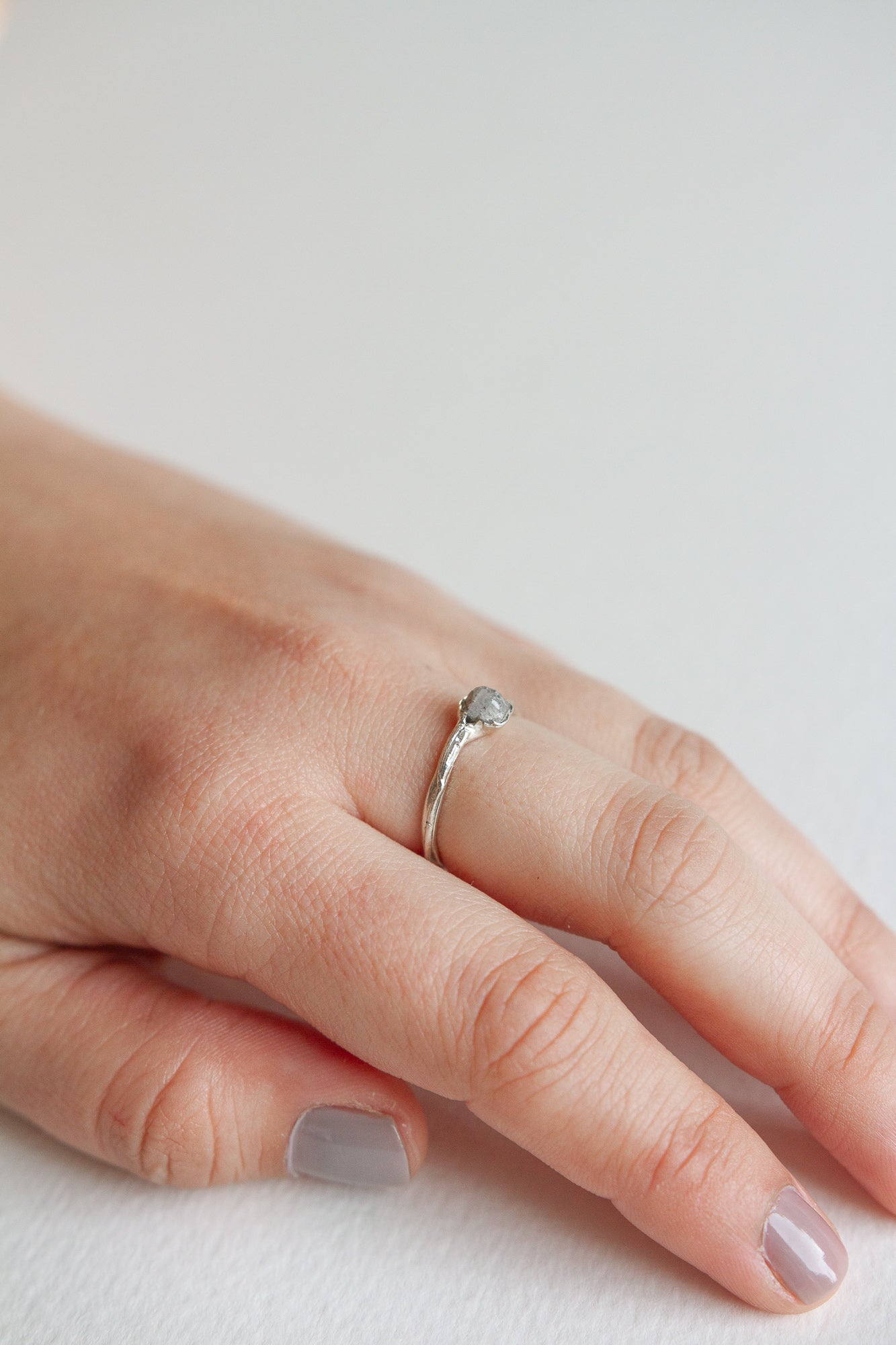 Hand wearing a handcrafted silver ring with a textured finish and an artisanal look.