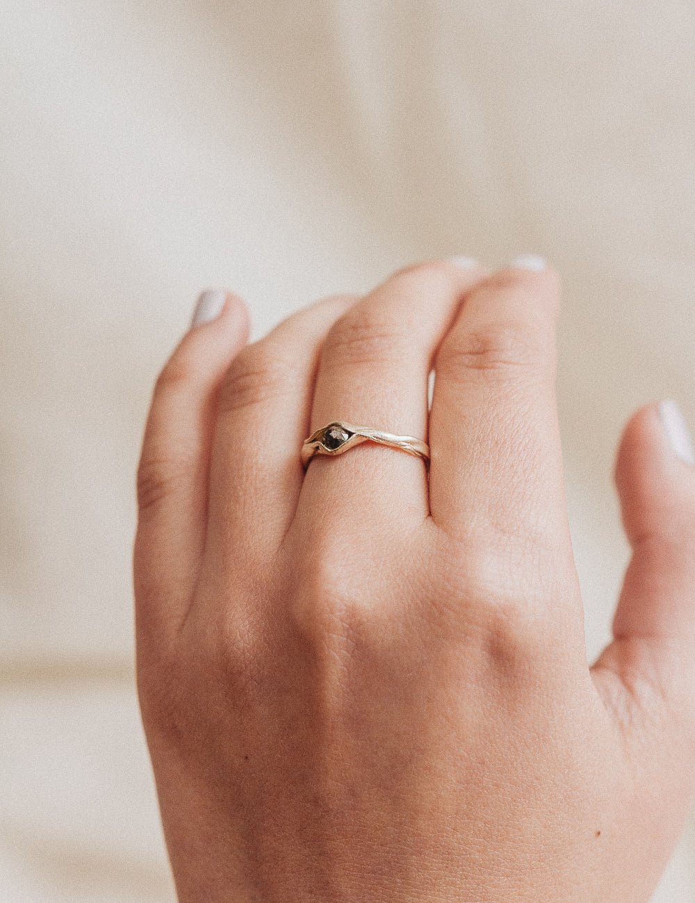 10k yellow gold salt-and-pepper diamond ring worn on a hand, photographed on a soft beige fabric background.