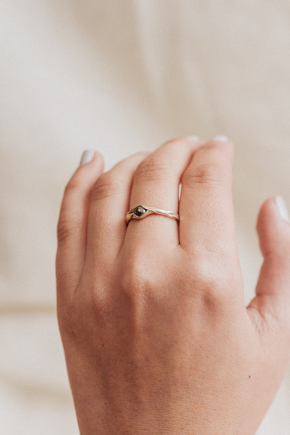 10k yellow gold salt-and-pepper diamond ring worn on a hand, photographed on a soft beige fabric background.