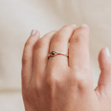 10k yellow gold salt-and-pepper diamond ring worn on a hand, photographed on a soft beige fabric background.
