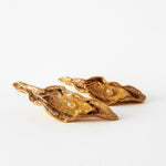 Flat lay of two Mustard variant Lettuce Leaf Earrings in gold-plated bronze, hand-painted in rust with glass granulation, placed on a white background.