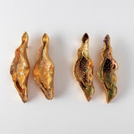 Flat lay of four Lettuce Leaf Earrings on a white background—two hand-painted mustard-yellow and two rust variant, all with glass granulation and gold-plated bronze settings.
