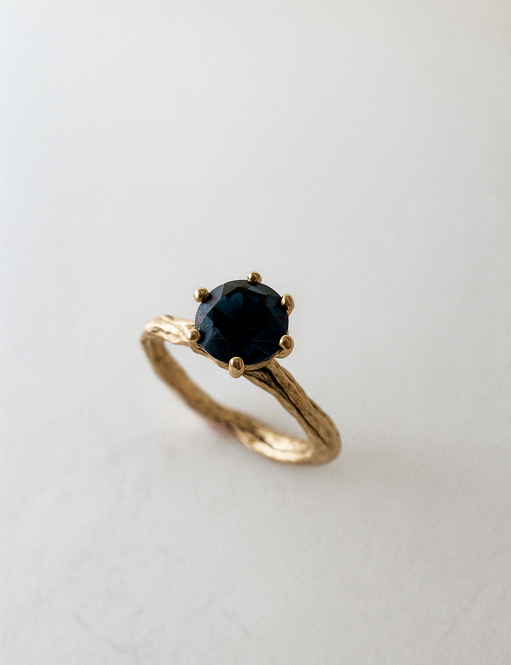 Angled side view of the 10k yellow gold London blue topaz ring highlighting its handcrafted textured band.