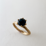 Angled side view of the 10k yellow gold London blue topaz ring highlighting its handcrafted textured band.